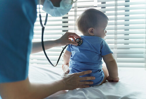 Asian female Pediatrician doctor examining her little baby patient with stethoscope in medical room at hospital.